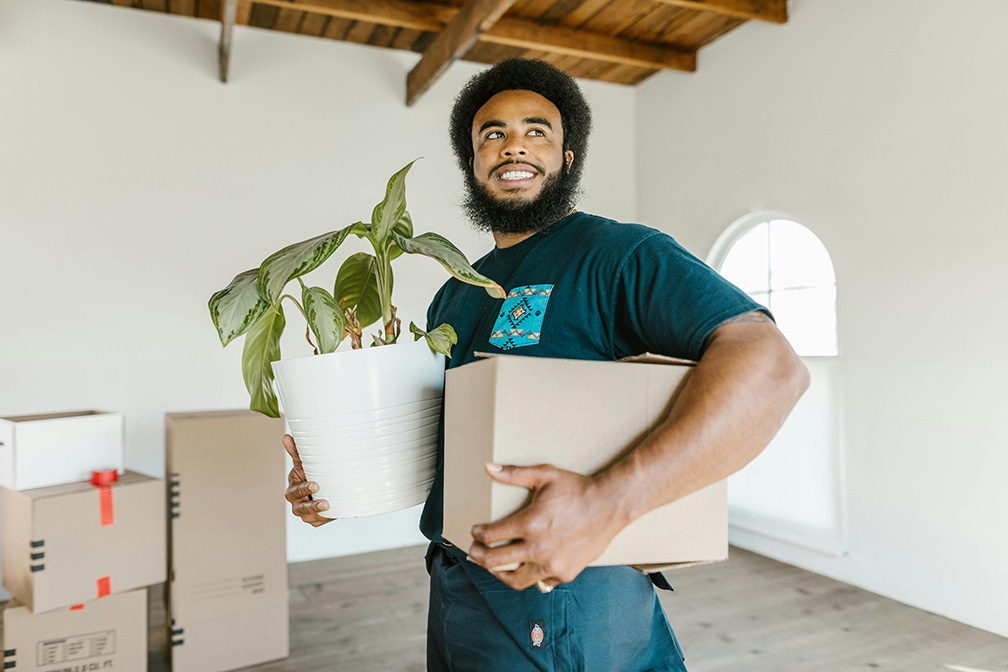 Man in Blue Crew Neck T-shirt Holding a Flower Pot and Box